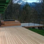 Photo d'une terrasse en bois avec un SPA habillé dans le même bois devant un chalet à Saint-Gervais